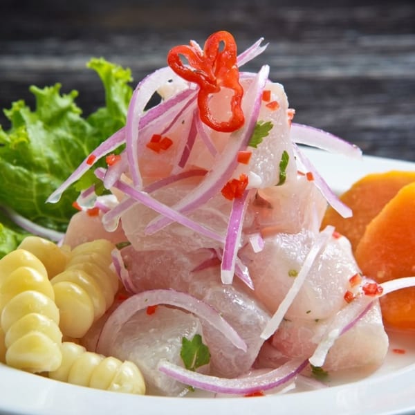 Peruvian ceviche with white fish, red onions, chili, corn, sweet potato, and lettuce.