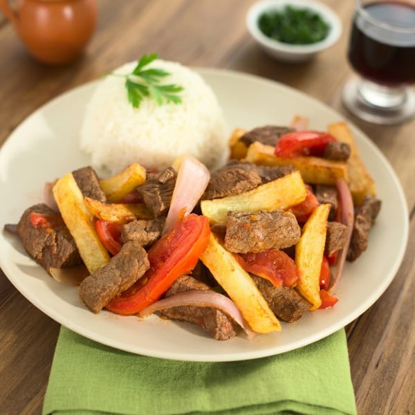 Peruvian Lomo Saltado with beef, fries, tomatoes, and onions, served with white rice.