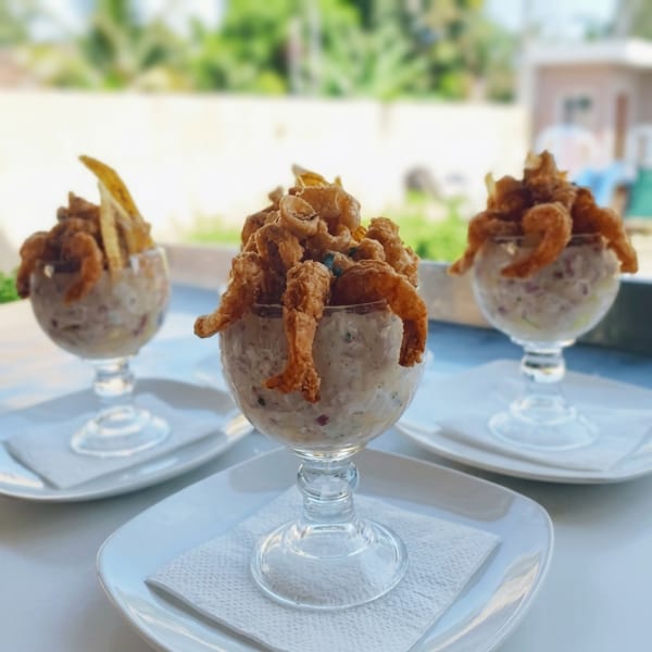 Three glasses of fried seafood and plantains over a creamy salad, on white plates.